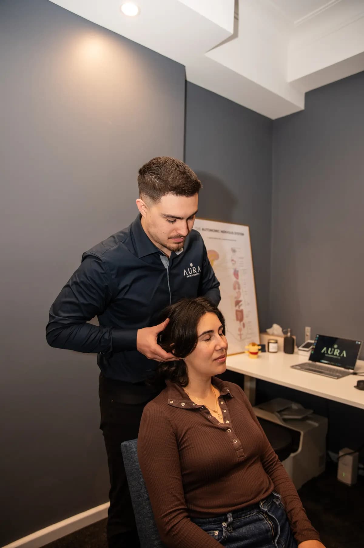 Dr Arthur Kaganovitch (Chiropractor) adjusting a relaxed patient's neck at Aura Chiropractic in Toorak