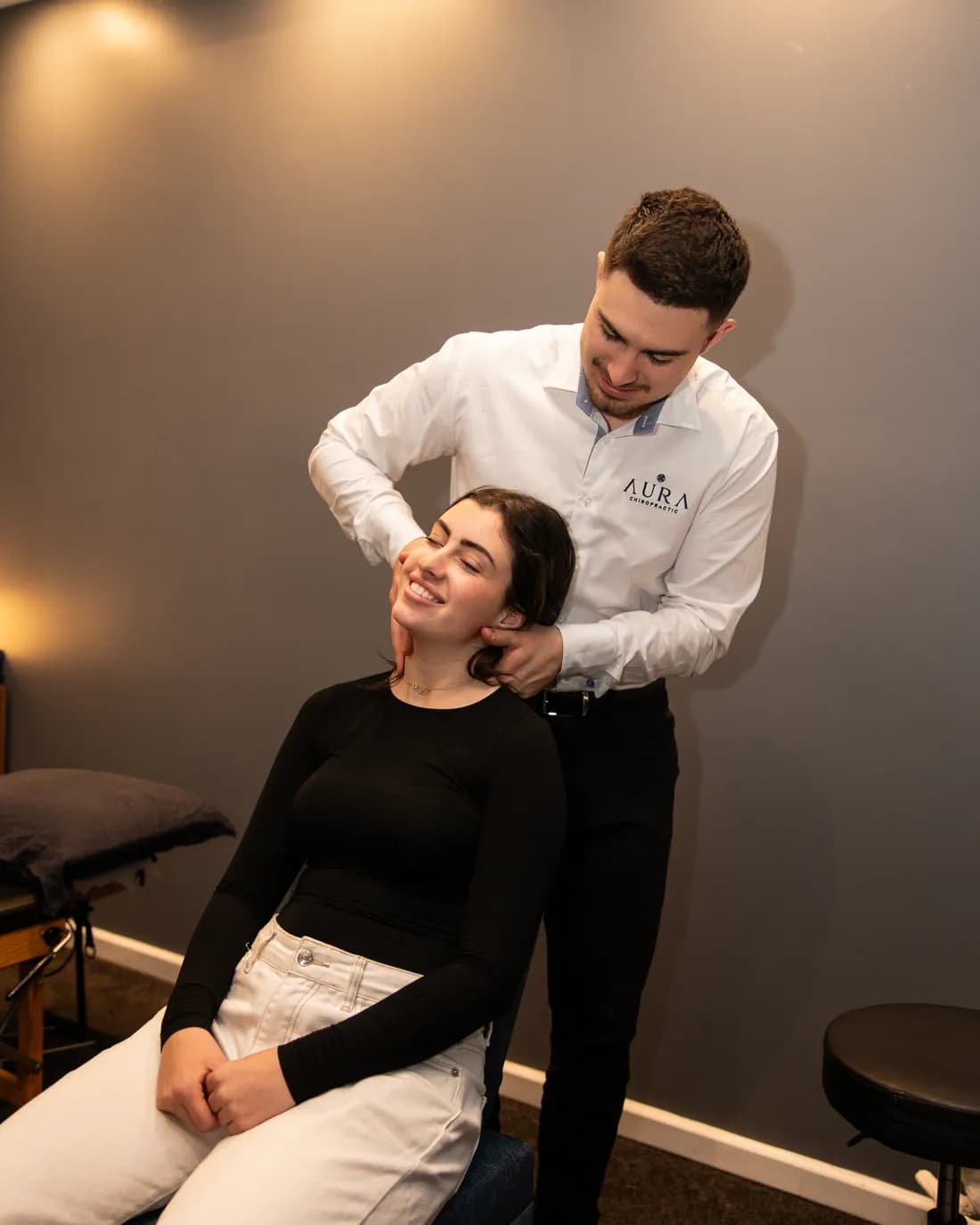Dr Arthur Kaganovitch adjusting a smiling patient's neck at Aura in Toorak