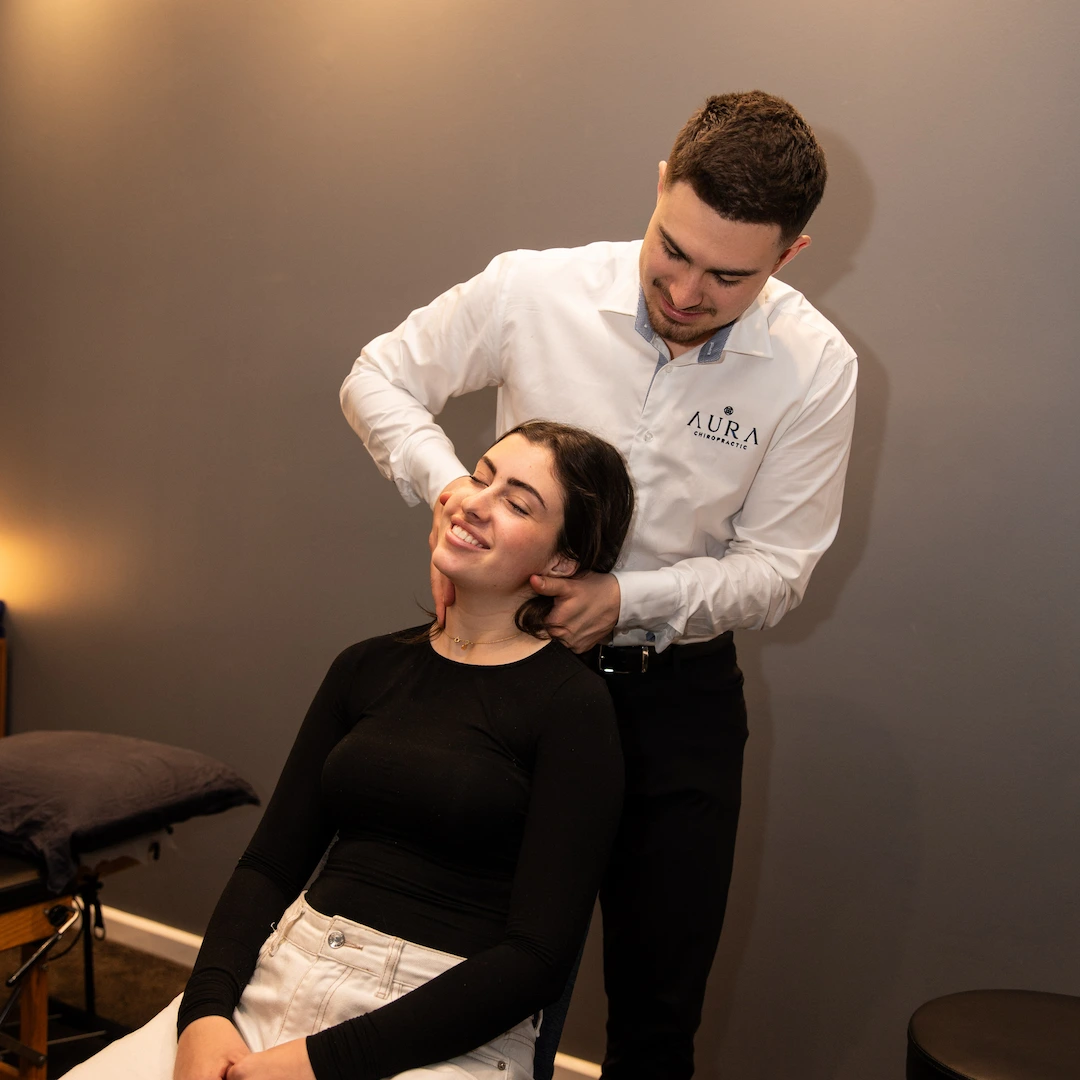 This is a photo of Dr Arthur performing a neck adjustment on his female patient. This is a high velocity low amplitude movement which seeks to improve mobility, range of motion and pain. Both Dr Arthur and the patient are smiling and relaxed